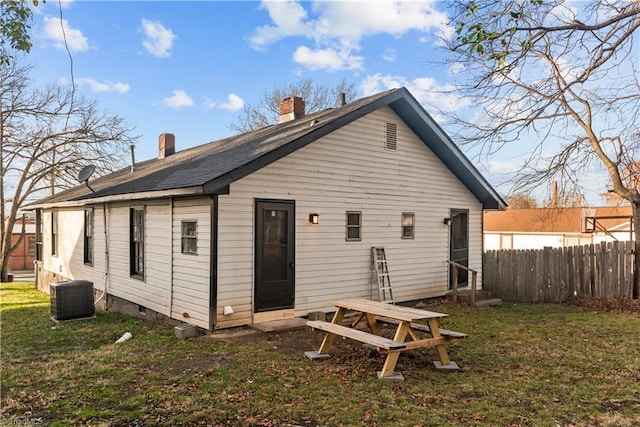 rear view of property featuring central AC unit and a lawn