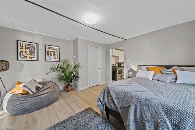 bedroom with ornamental molding and light hardwood / wood-style floors