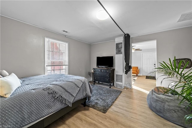 bedroom featuring ornamental molding and light wood-type flooring