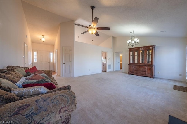 carpeted living room with ceiling fan with notable chandelier and high vaulted ceiling