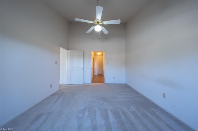 empty room with dark carpet, high vaulted ceiling, and ceiling fan