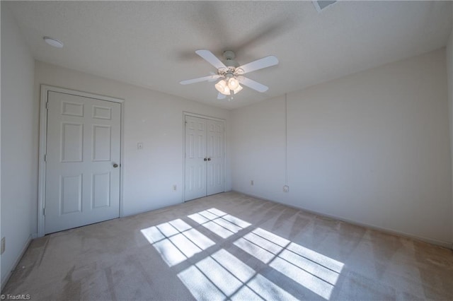 empty room with ceiling fan and light colored carpet