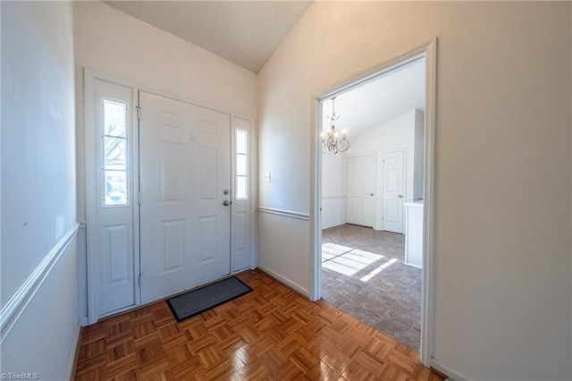 entryway with vaulted ceiling, parquet floors, and an inviting chandelier