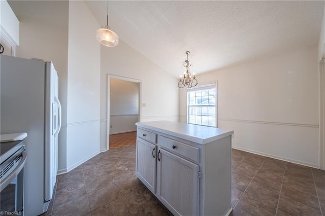 kitchen featuring stove, lofted ceiling, decorative light fixtures, white fridge, and a chandelier