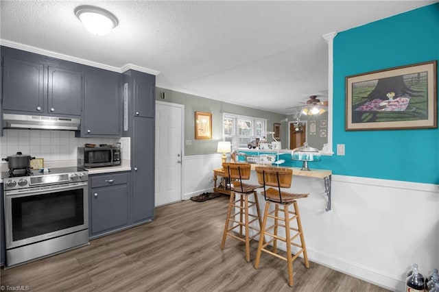 kitchen with dark wood-type flooring, gray cabinetry, a kitchen bar, stainless steel electric stove, and kitchen peninsula