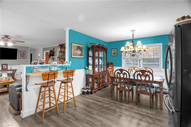 dining room featuring ceiling fan with notable chandelier and wood-type flooring