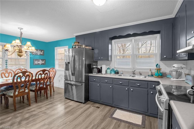 kitchen with sink, appliances with stainless steel finishes, plenty of natural light, a notable chandelier, and decorative light fixtures