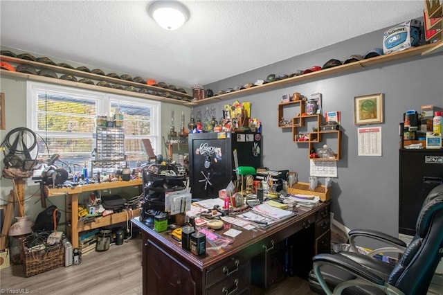 office area with a textured ceiling, light wood-type flooring, and a workshop area