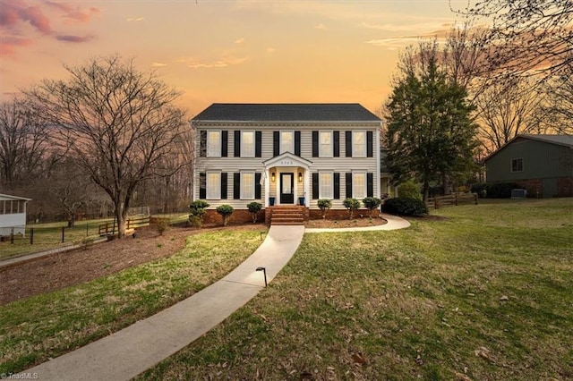 colonial home featuring a front yard and fence