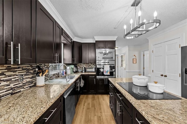 kitchen featuring crown molding, light stone countertops, light wood-style floors, stainless steel appliances, and a sink