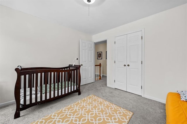 carpeted bedroom featuring a closet, a nursery area, and baseboards