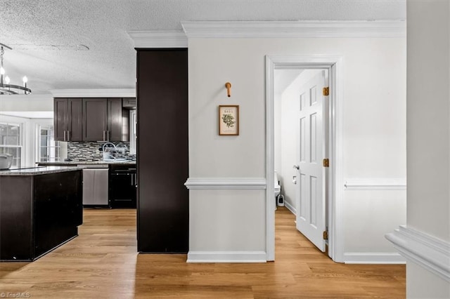 kitchen with tasteful backsplash, light wood-style flooring, stainless steel dishwasher, and ornamental molding