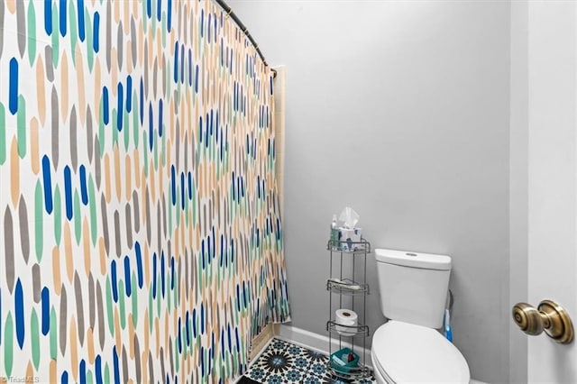 bathroom with a shower with curtain, toilet, and baseboards