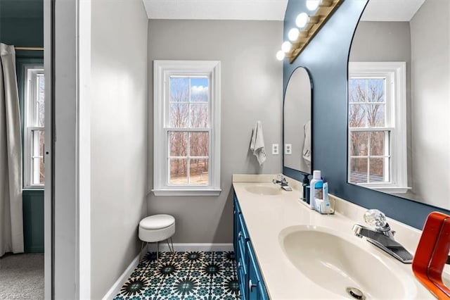 bathroom featuring a healthy amount of sunlight, baseboards, and a sink