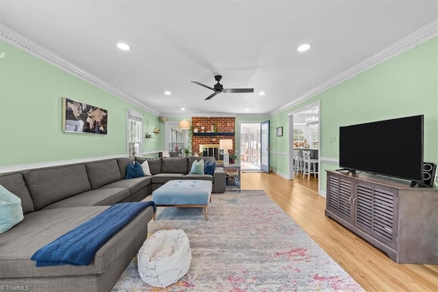 living area with light wood finished floors, recessed lighting, a fireplace, ceiling fan, and crown molding