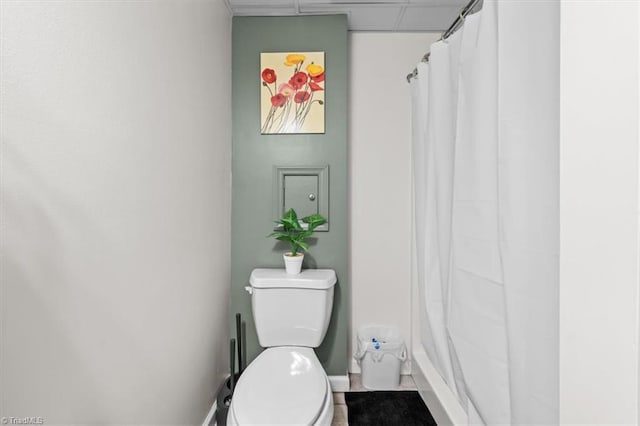 bathroom with a shower with shower curtain, toilet, and a paneled ceiling