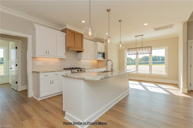 kitchen with white cabinetry, appliances with stainless steel finishes, and a center island with sink