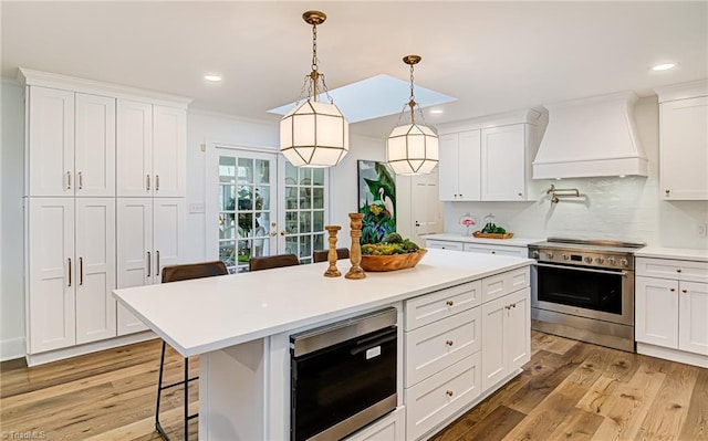 kitchen featuring premium range hood, stainless steel appliances, and white cabinetry