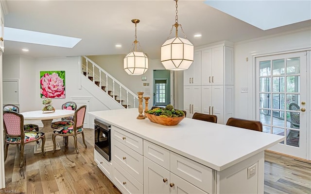 kitchen featuring stainless steel microwave, white cabinets, a healthy amount of sunlight, and pendant lighting