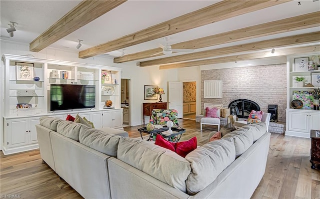 living room with light hardwood / wood-style floors, ceiling fan, beamed ceiling, and a brick fireplace