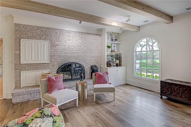 living area featuring light hardwood / wood-style floors, beam ceiling, and a fireplace