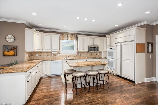 kitchen with a sink, a kitchen breakfast bar, dark wood-style floors, white appliances, and white cabinets