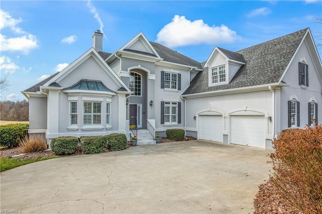 view of front facade with concrete driveway, stucco siding, an attached garage, and a shingled roof