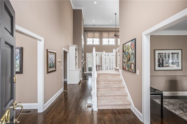 entrance foyer with baseboards, a high ceiling, ornamental molding, and dark wood-style flooring