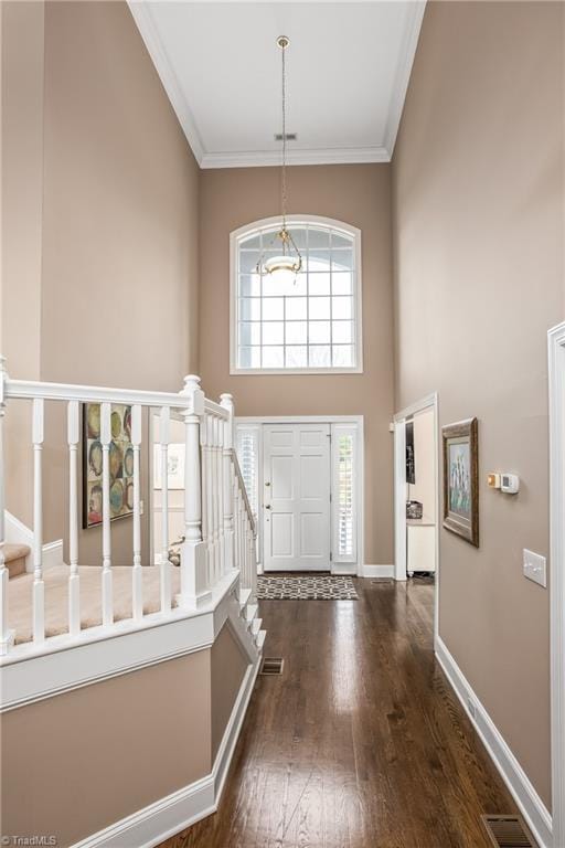 entryway featuring visible vents, dark wood-type flooring, a high ceiling, crown molding, and baseboards