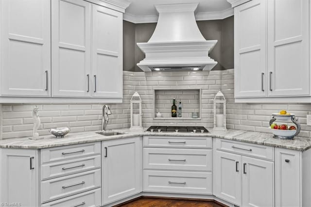 1905 Regents Park Ln, Greensboro, NC 27455 - kitchen with custom range hood, stainless steel gas stovetop, a sink, white cabinetry, and tasteful backsplash