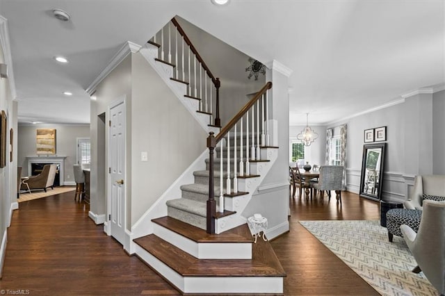 1905 Regents Park Ln, Greensboro, NC 27455 - stairs featuring ornamental molding, a fireplace, recessed lighting, wood finished floors, and a chandelier