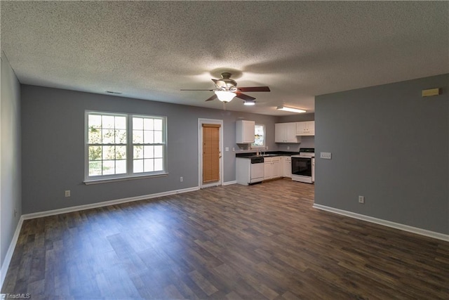unfurnished living room with a ceiling fan, plenty of natural light, dark wood-style floors, and a textured ceiling