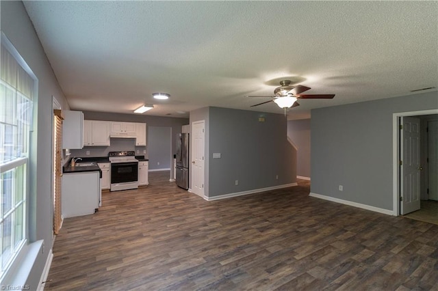 kitchen featuring range with electric stovetop, open floor plan, freestanding refrigerator, dark countertops, and a textured ceiling
