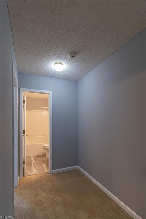 spare room with carpet flooring, baseboards, and a textured ceiling