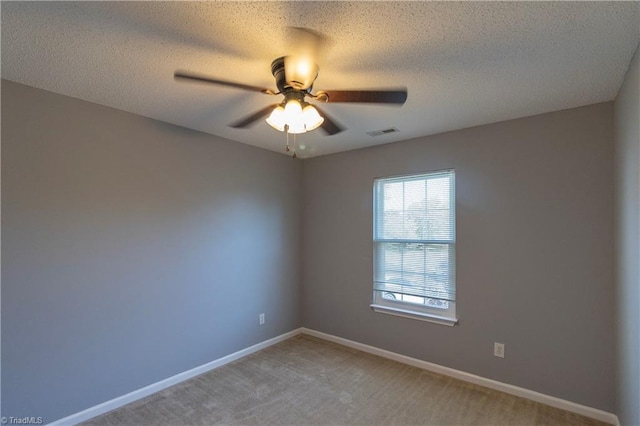 spare room featuring a ceiling fan, light colored carpet, baseboards, and a textured ceiling
