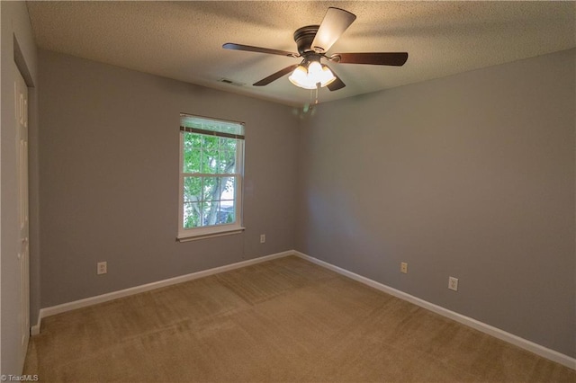 unfurnished room with a ceiling fan, light colored carpet, baseboards, and a textured ceiling