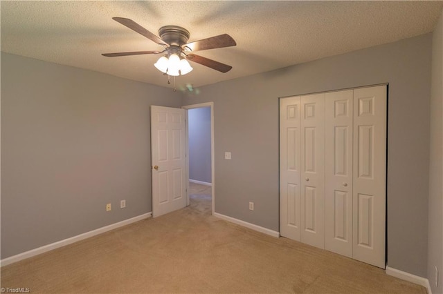 unfurnished bedroom featuring light colored carpet, baseboards, a closet, and ceiling fan