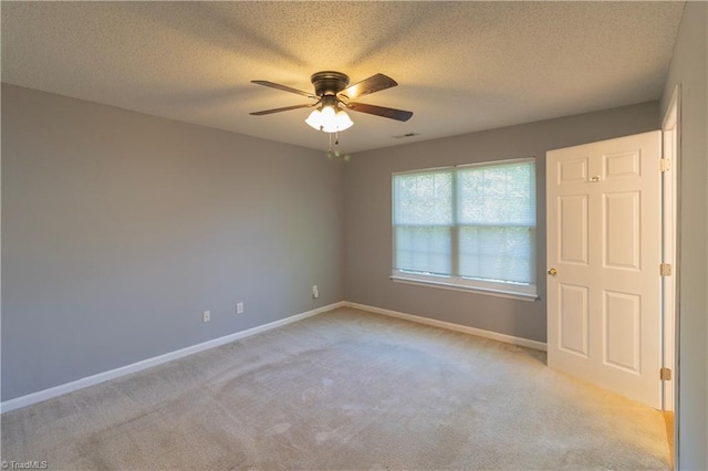 unfurnished bedroom featuring light carpet, baseboards, a textured ceiling, and ceiling fan