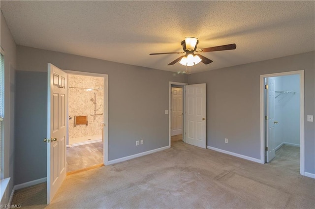 unfurnished bedroom featuring light carpet, baseboards, a spacious closet, and a textured ceiling
