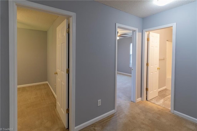 hall featuring carpet, a textured ceiling, and baseboards