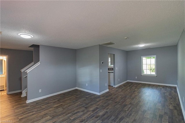 spare room with a textured ceiling, dark wood-style floors, baseboards, and stairs