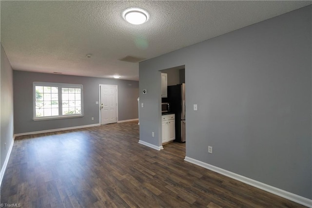 unfurnished living room with a textured ceiling, dark wood-type flooring, and baseboards