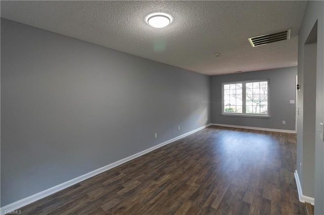 spare room featuring dark wood-style floors, baseboards, and a textured ceiling