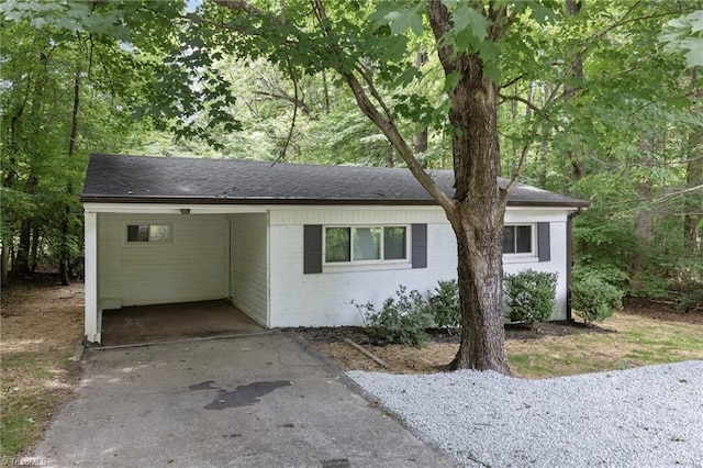 view of front of home with a carport, brick siding, driveway, and a shingled roof