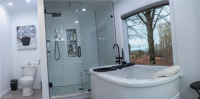 bathroom featuring toilet, a stall shower, a freestanding tub, and baseboards
