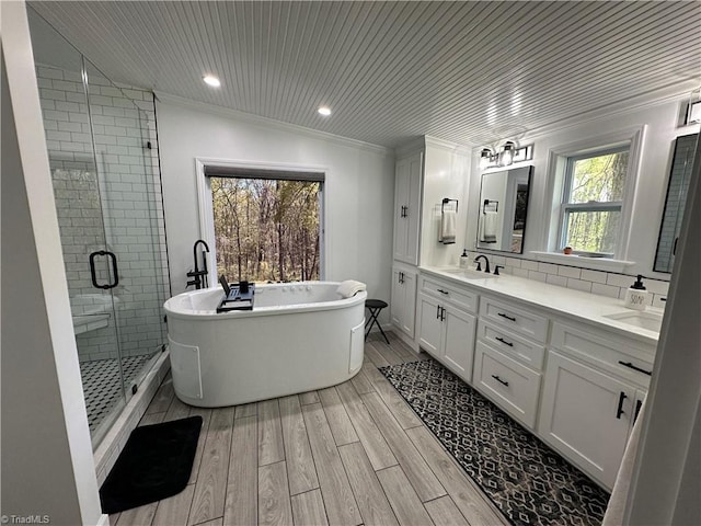 bathroom featuring a freestanding bath, a sink, a shower stall, double vanity, and wood finish floors