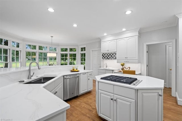 kitchen with ornamental molding, stainless steel appliances, a sink, and a center island