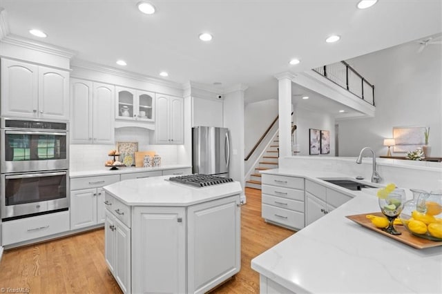 kitchen with appliances with stainless steel finishes, white cabinetry, a sink, and a kitchen island