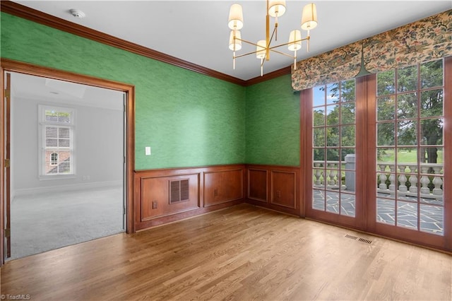 unfurnished dining area with wainscoting, visible vents, and wood finished floors