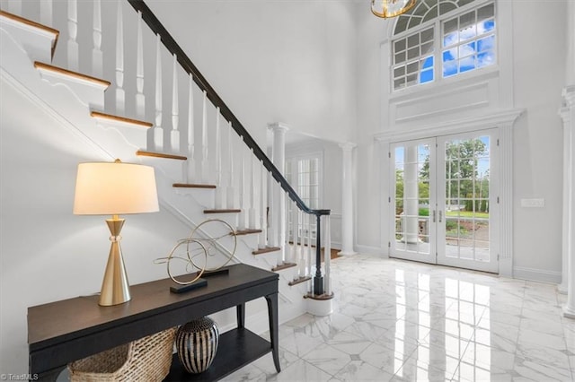 entryway with baseboards, marble finish floor, a high ceiling, and ornate columns